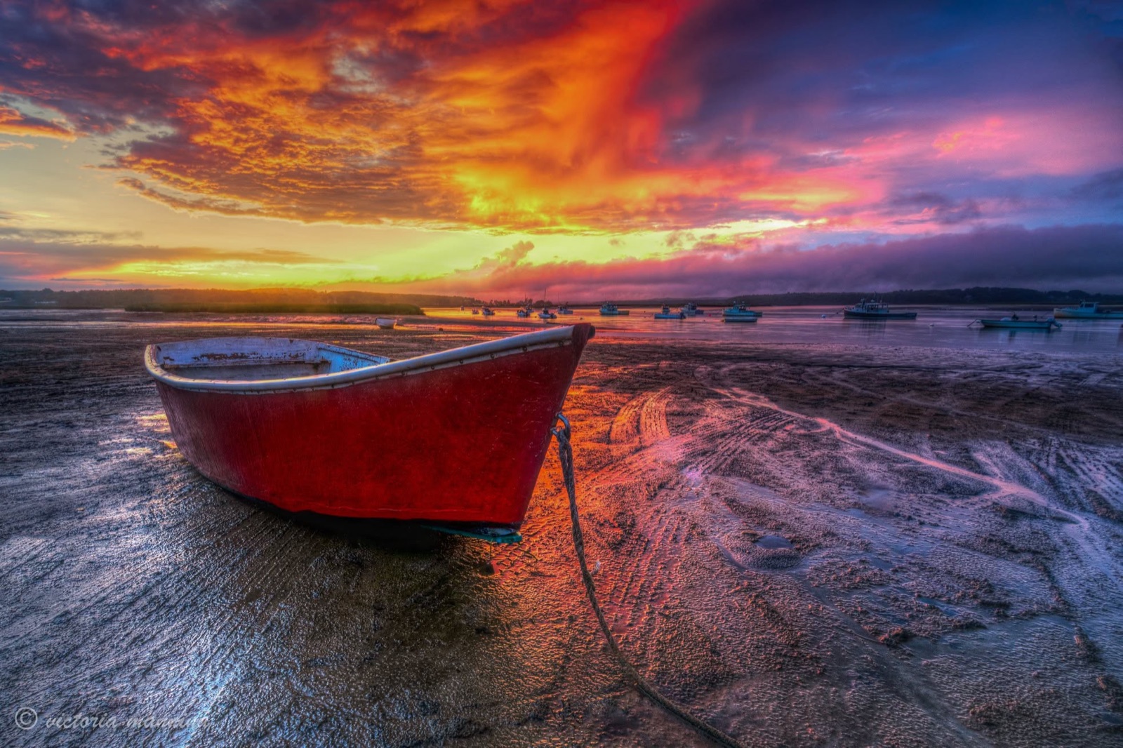 red rowboat on mudflat under vivid sunset sky