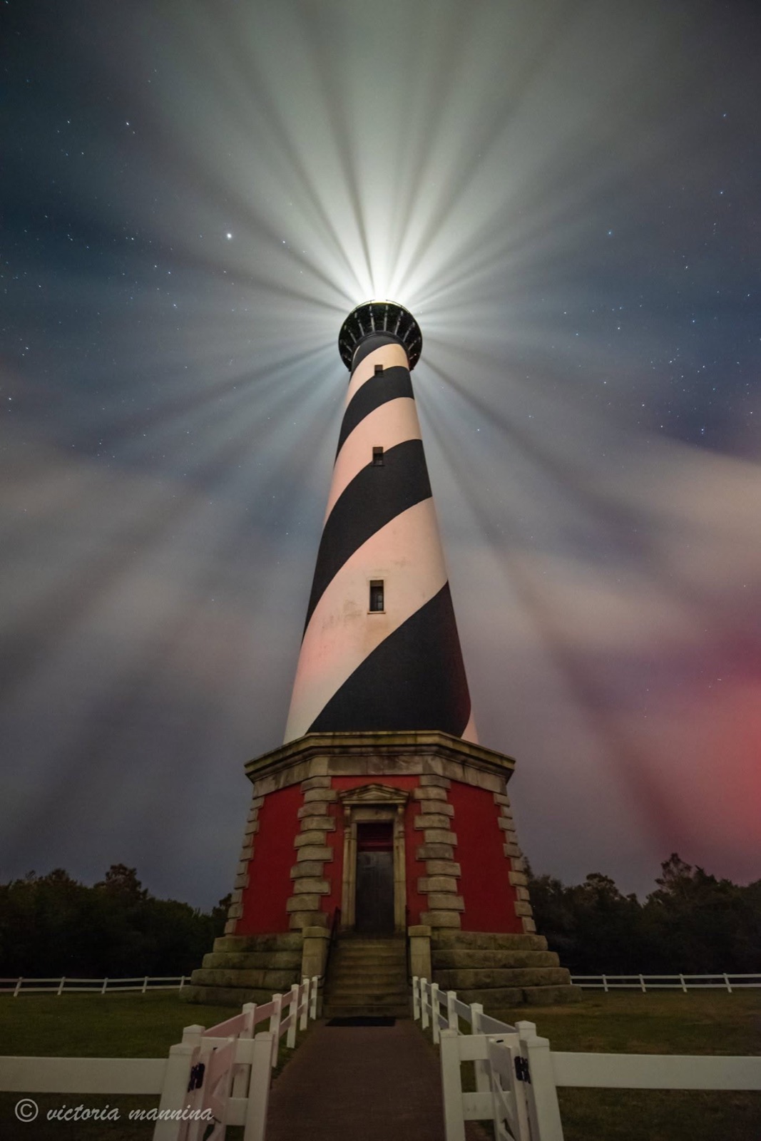 Lighthouse tower with radiating light beam under night sky