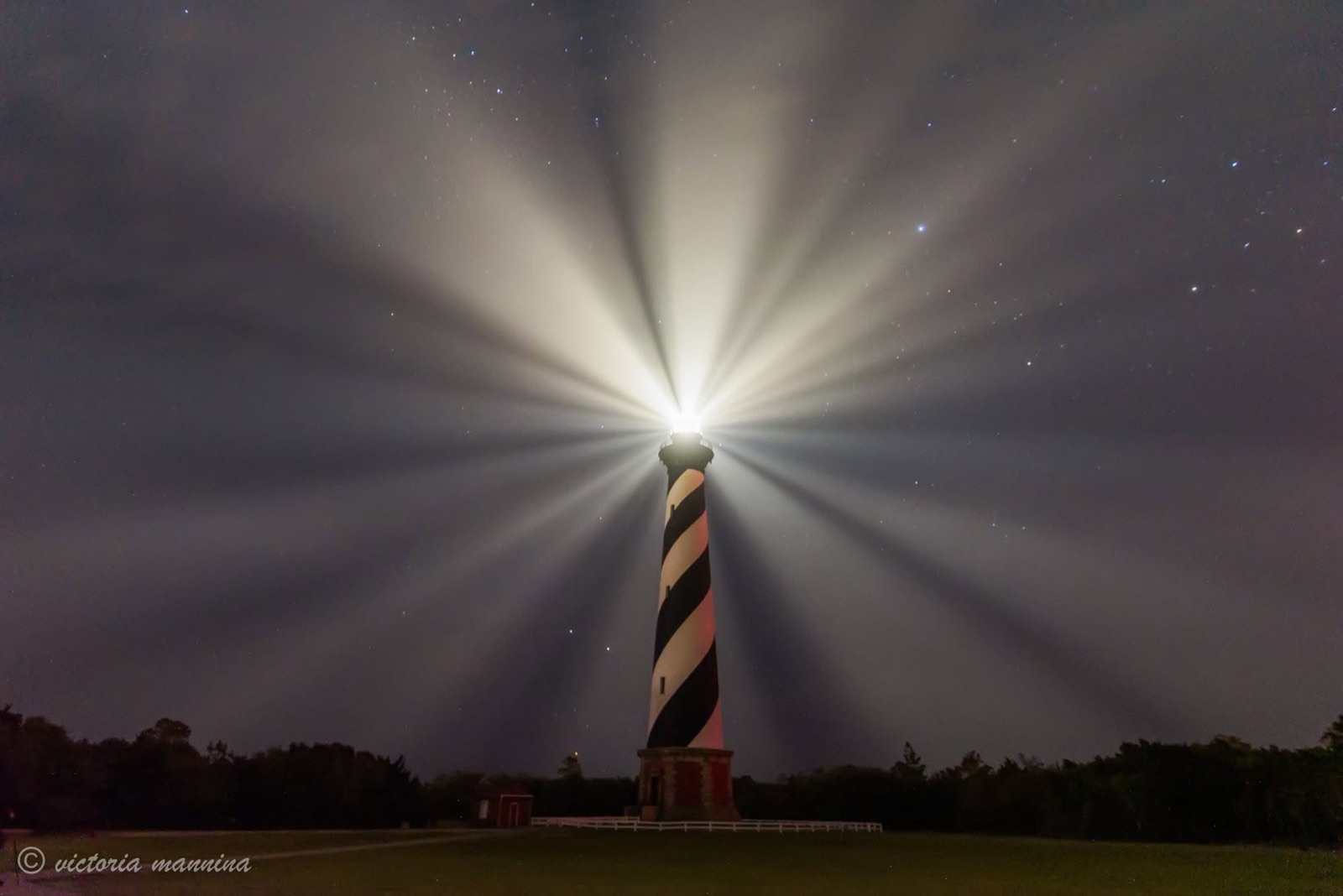 Cape Hatteras lighthouse beaming light into starry night sky