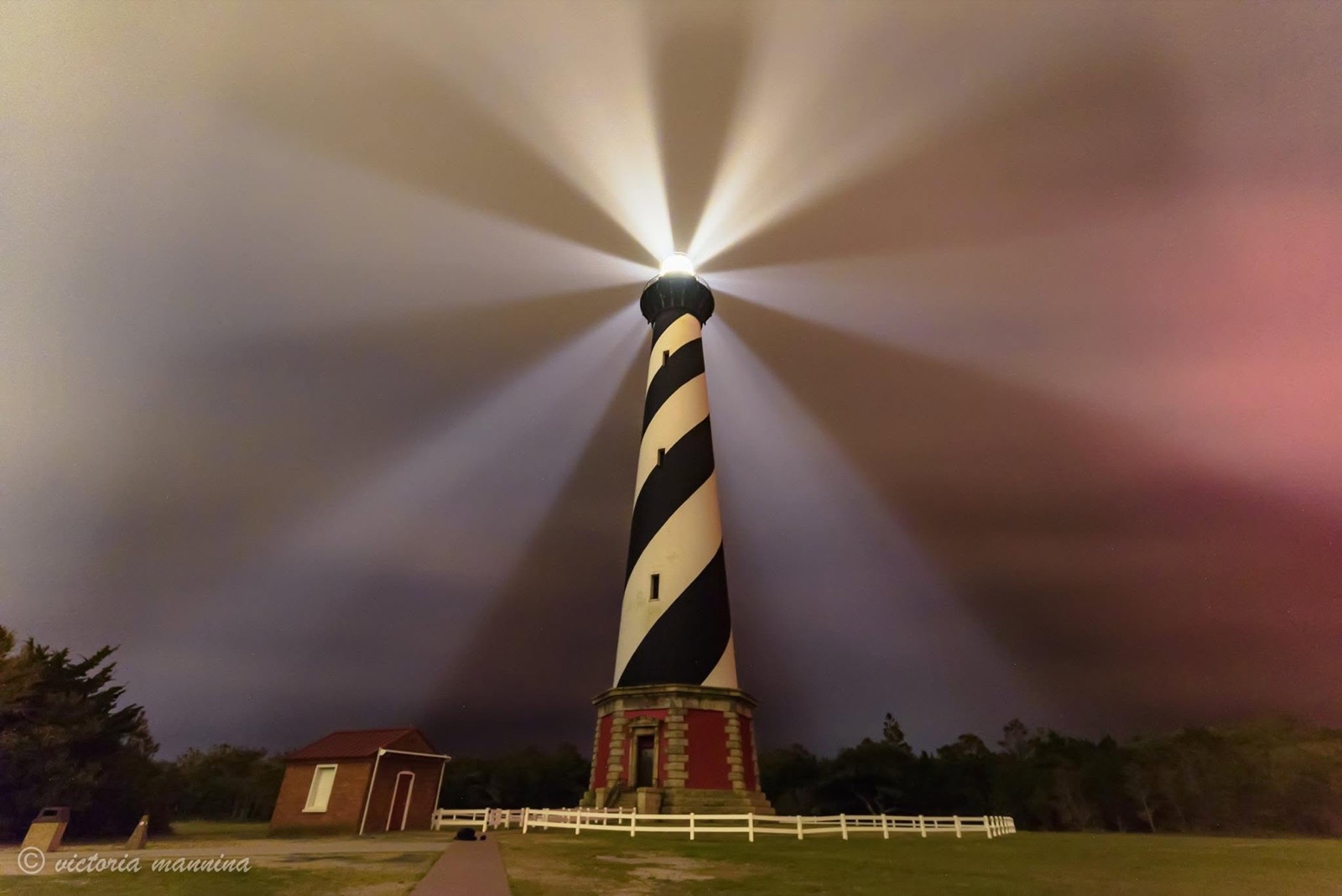 Lighthouse beam cutting through stormy dusk clouds