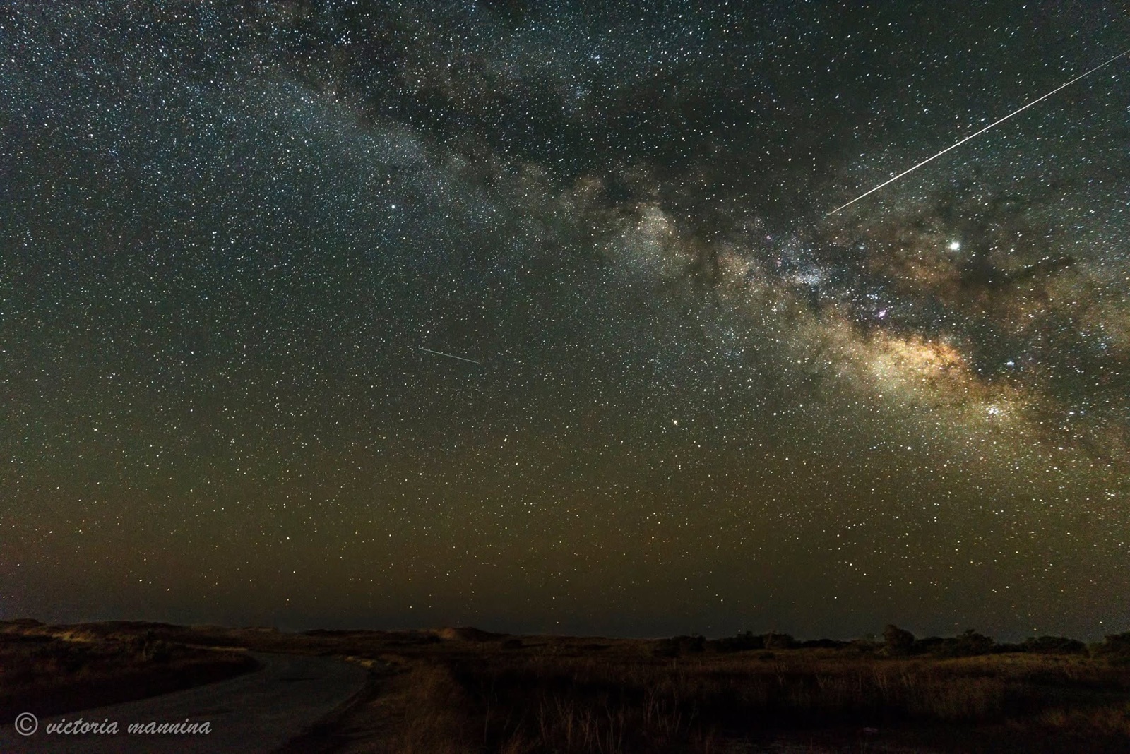 Milky Way and meteor streaks above coastal dunes and road